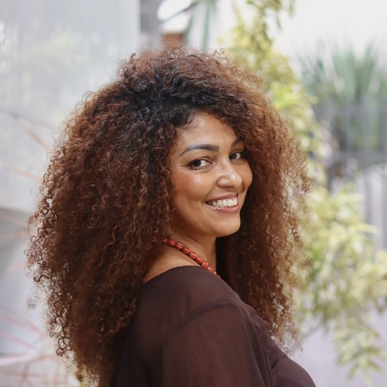 Cliente Reflora com cabelo cacheado longo